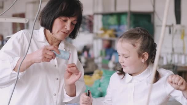 Grootmoeder met kleindochter meet de stof voor het naaien — Stockvideo