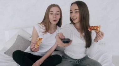 Kız arkadaşlar pizza yer ve evde televizyon izlerler.