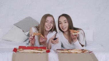 Kız arkadaşlar pizza yer ve evde televizyon izlerler.