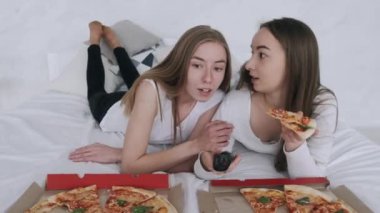 Kız arkadaşlar pizza yer ve evde televizyon izlerler.