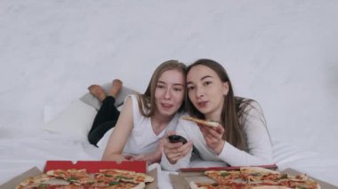 Kız arkadaşlar pizza yer ve evde televizyon izlerler.
