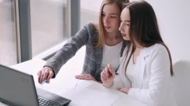 Ofiste dizüstü bilgisayarı olan iki kadın.