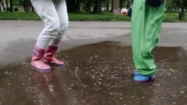 Yağmur parkında oynayan çizmeli komik çocuk.