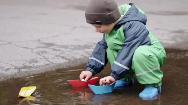 Lustiges Kind in Regenstiefeln spielt im Regenpark — Stockvideo