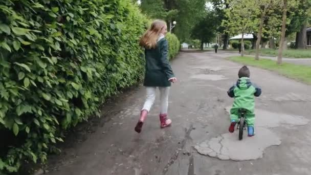 Chico divertido con botas de lluvia jugando en un parque de lluvia — Vídeo de stock