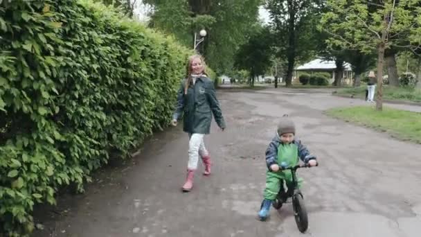 Lustiges Kind in Regenstiefeln spielt im Regenpark — Stockvideo