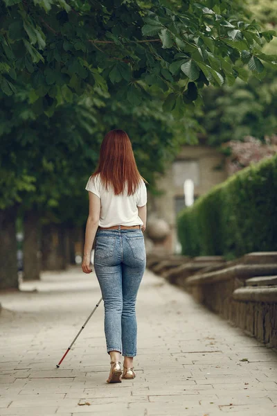 Young blind person with long cane walking in a city