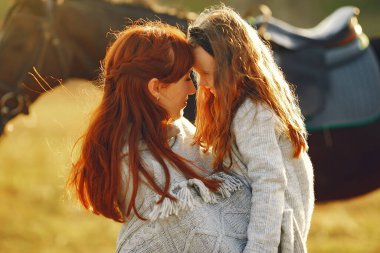 Anne ve kızı bir tarlada bir atla oynuyorlar.