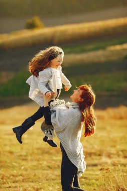 Anne ve küçük kızı sonbahar tarlasında oynuyorlar.