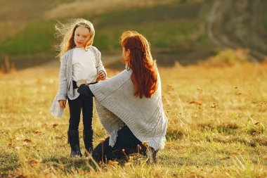 Anne ve küçük kızı sonbahar tarlasında oynuyorlar.