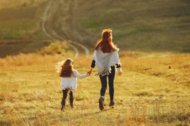 Anne ve küçük kızı sonbahar tarlasında oynuyorlar.