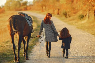 Anne ve kızı bir tarlada bir atla oynuyorlar.