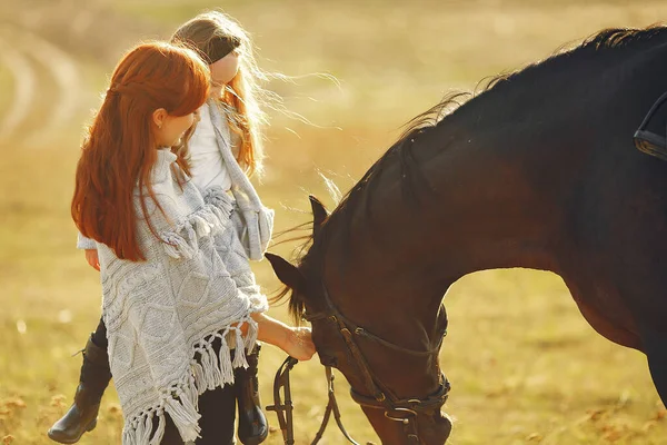 Мать и дочь в поле играют с лошадью — стоковое фото