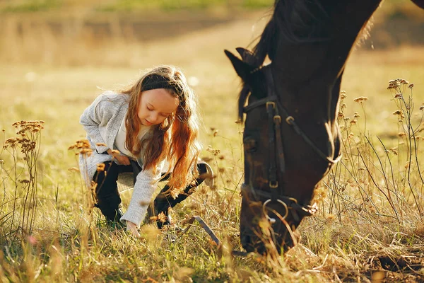 Menina bonito em um campo de outono com cavalo — Fotografia de Stock