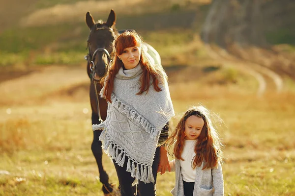 Мать и дочь в поле играют с лошадью — стоковое фото