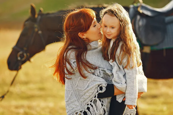 Moeder en dochter in een veld spelen met een paard — Stockfoto