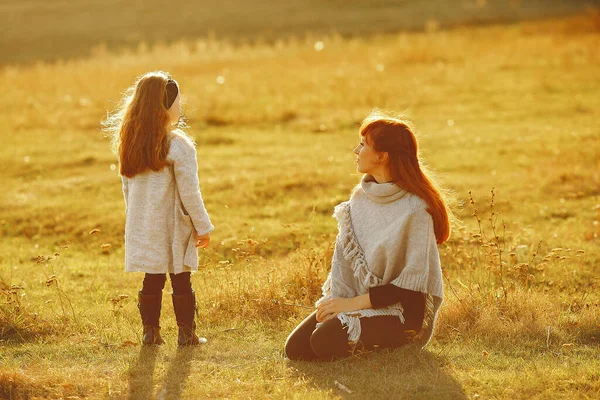 Mor med liten dotter som leker på ett höstfält — Stockfoto