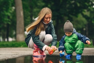 Yağmur parkında oynayan çizmeli komik çocuk.