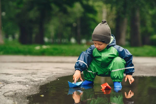 Chico divertido con botas de lluvia jugando en un parque de lluvia — Foto de Stock