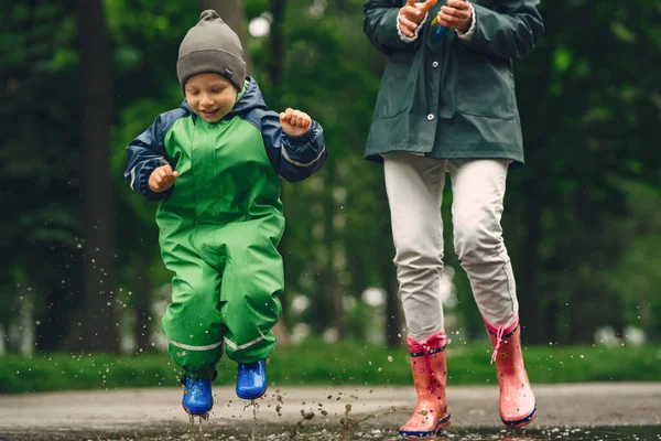 Lucu anak dalam sepatu bot hujan bermain di taman hujan — Stok Foto