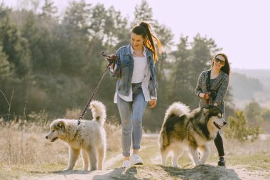 Bir bahar tarlasında köpekli iki şık kız.