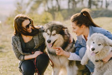 Bir bahar tarlasında köpekli iki şık kız.