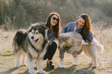 Bir bahar tarlasında köpekli iki şık kız.