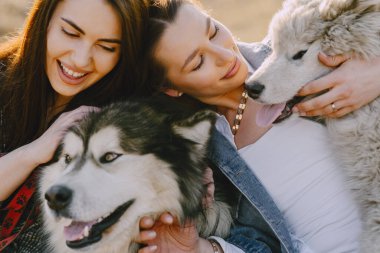 Bir bahar tarlasında köpekli iki şık kız.
