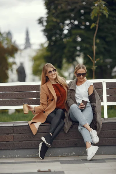 Meninas sentadas em uma primavera sity e segurar café em sua mão — Fotografia de Stock