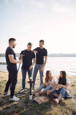 Gençler dışarıda nargile içerek pizza yiyor.