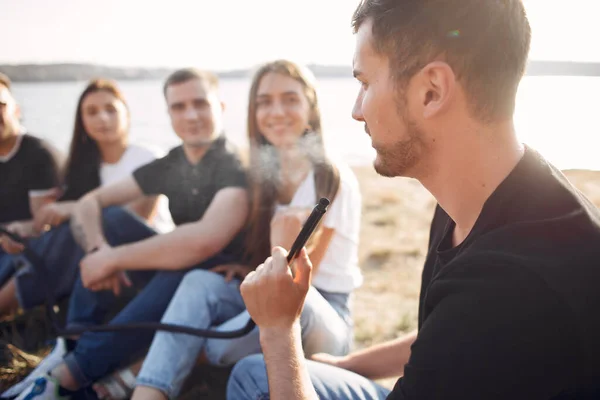 Young people eating pizza smoking shisha outside