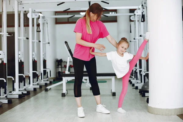 Anne ve küçük kızı spor salonunda jimnastik yapıyor.