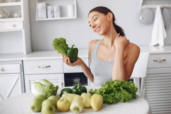 Menina bonita e desportiva em uma cozinha com um legumes — Fotografia de Stock