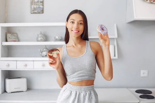 Красива дівчина стоїть на кухні з пончиком — стокове фото