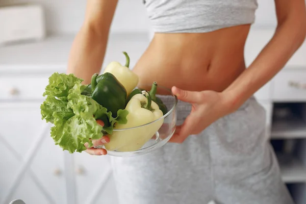 Beautiful and sporty girl in a kitchen with a vegetables — Stock Photo, Image
