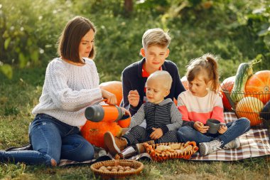 Balkabaklarının yanındaki bahçede oturan büyük bir aile.