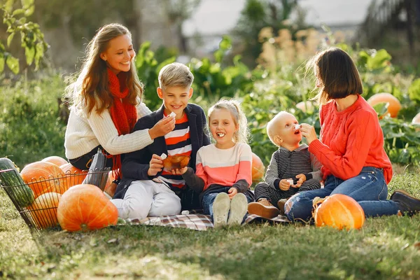 Big family sitting on a garden near many pumpkins — Stock Photo, Image