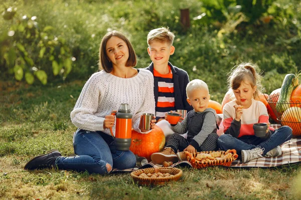 Big family sitting on a garden near many pumpkins — Stock Photo, Image