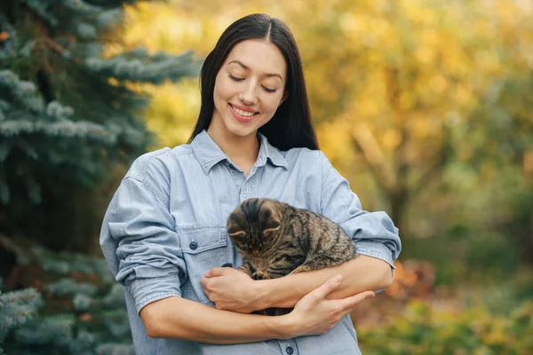 Dívka v modré košili stojící na stromech pozadí — Stock fotografie