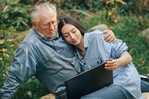 Дівчина навчає свого діда користуватися ноутбуком — стокове фото