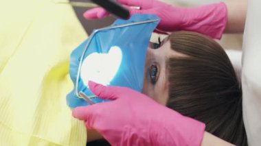 Bir kadın diş hekimi tek kullanımlık eldivenlerle diş tedavisi yapıyor.