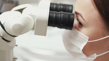 Dişi bir endodontist mikroskop altında kanalları tedavi ediyor..