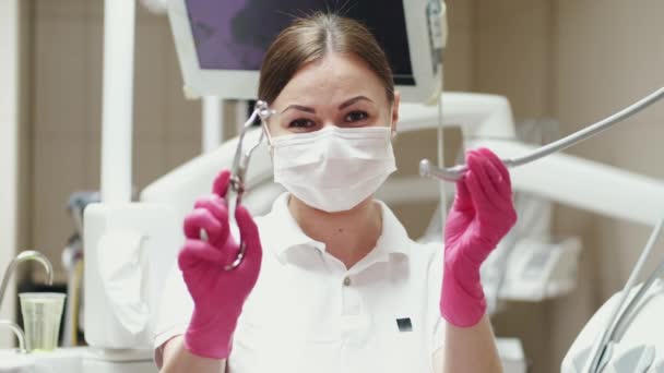 En kvinnlig tandläkare ID visar tandläkare borrar — Stockvideo