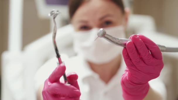 En kvinnlig tandläkare ID visar tandläkare borrar — Stockvideo