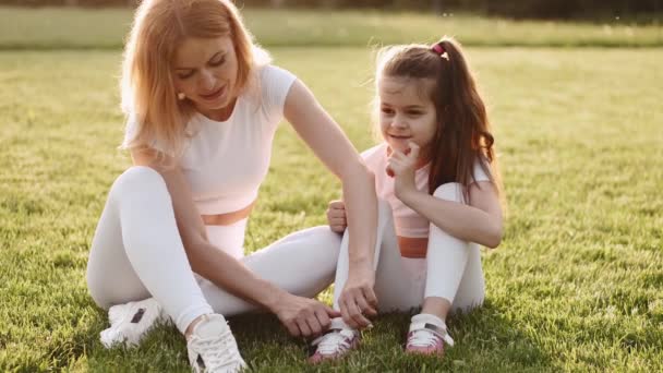 Bela mãe e filha estão ouvindo música no gramado — Vídeo de Stock