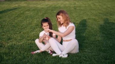 Anne ve kızı otların üzerinde müzik dinliyorlar.