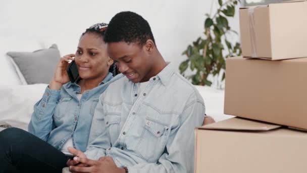 Νεαρό Αφροαμερικανό ζευγάρι κάθεται στο μοντέρνο διαμέρισμα με κουτιά — Αρχείο Βίντεο