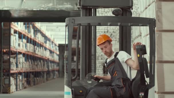 Jeune travailleur en uniforme i assis dans une voiture de chariot élévateur — Video