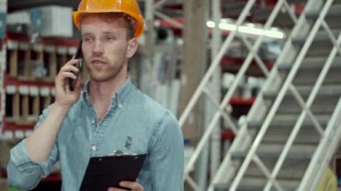 Miğferli fabrika mühendisi üretimi kontrol ediyor.