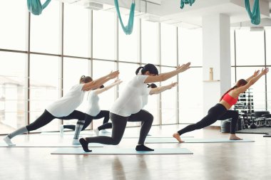 Hamile kadınlar bir koçla yoga yapıyor.